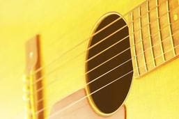 A close up of a yellow acoustic guitar.