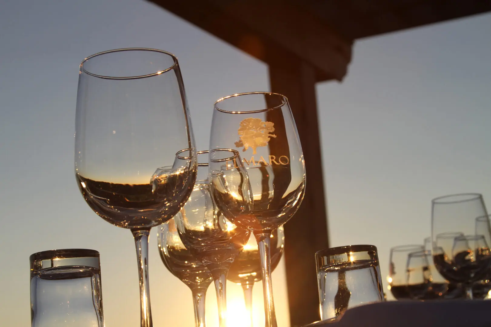 A group of wine glasses on a table at sunset.