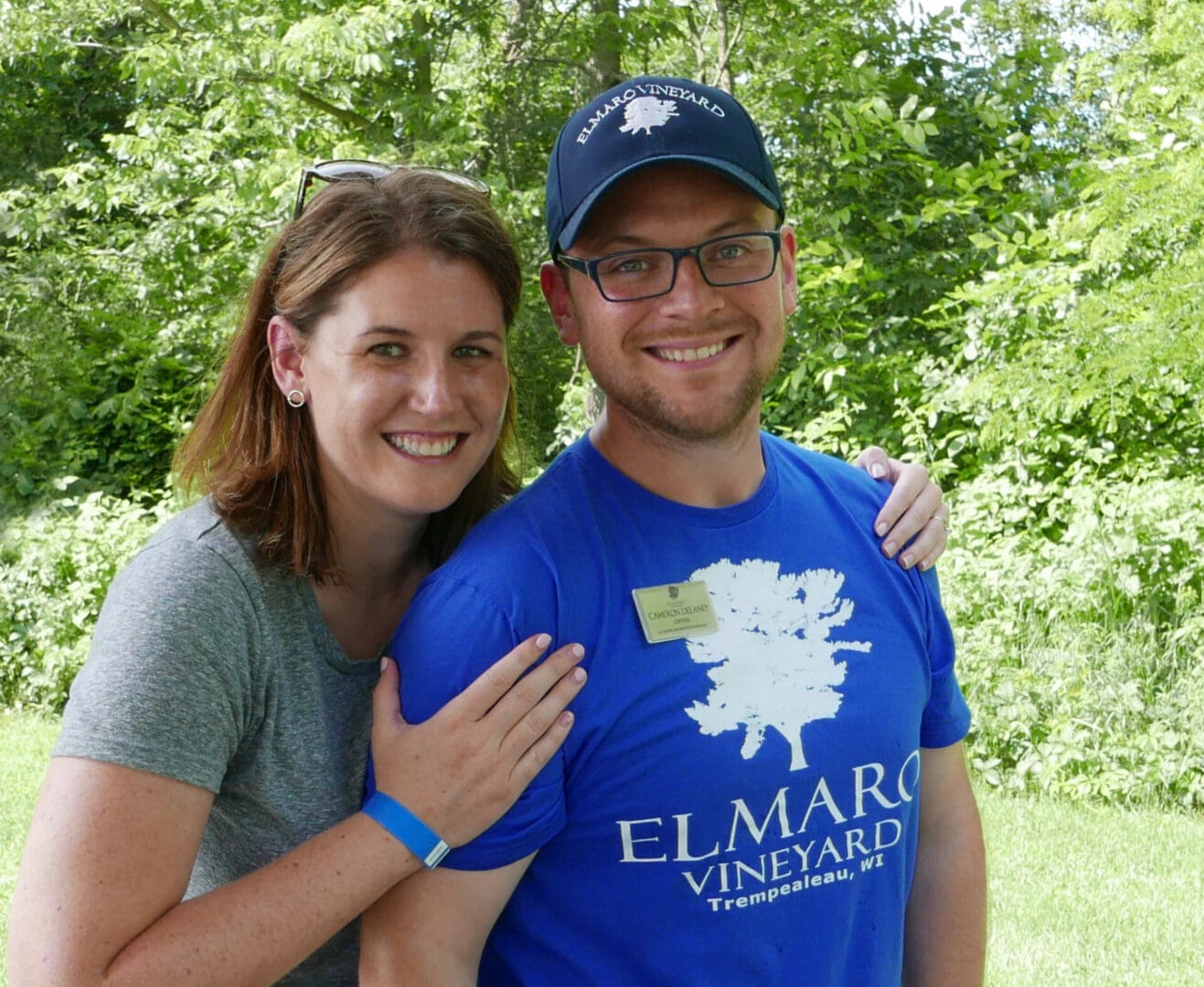 A man and woman posing for a photo in the woods.