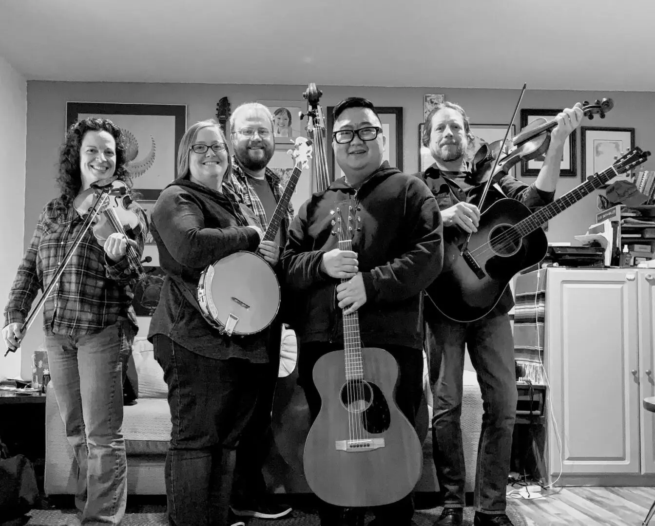 A group of people posing with guitars and banjos in a living room.