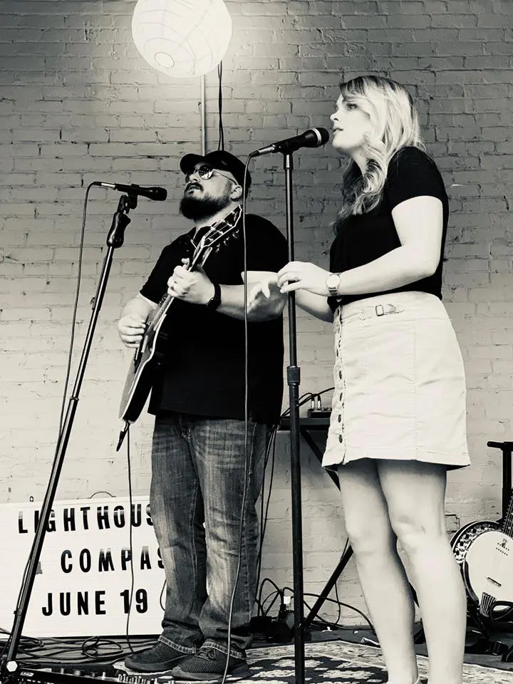 A man and woman singing in front of microphones.