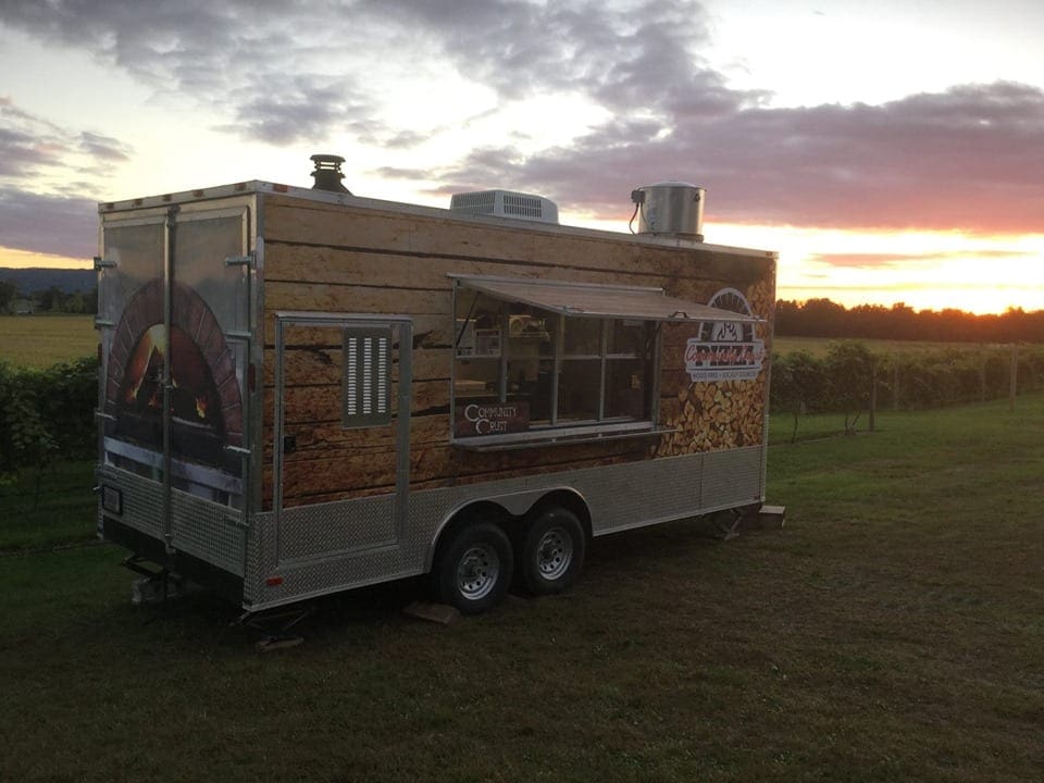 A food truck in a field at sunset.