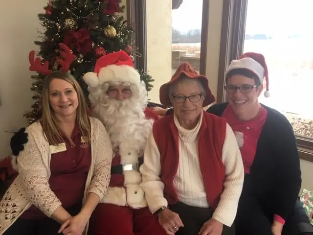 Three elderly women posing for a photo with santa claus.