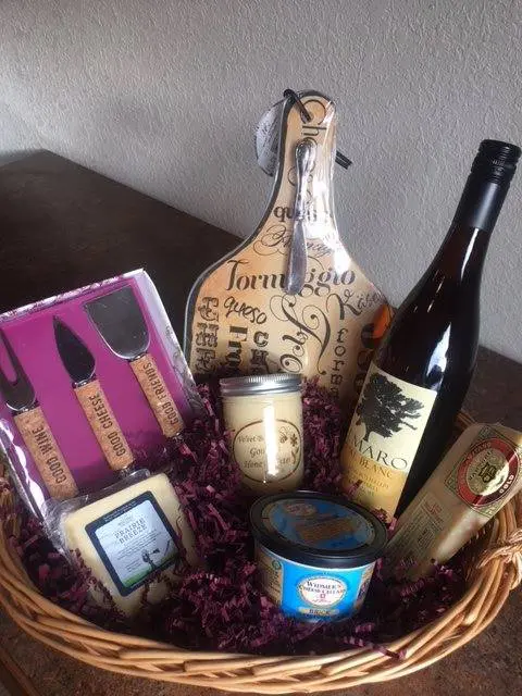 A basket with wine, cheese, and other items.
