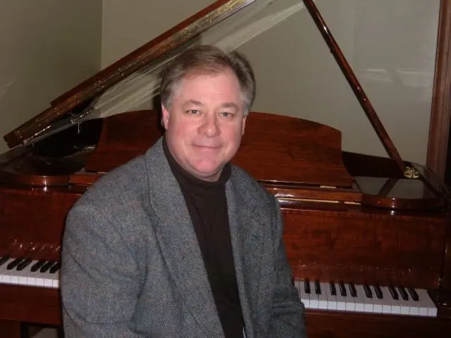 A man sitting in front of a piano.