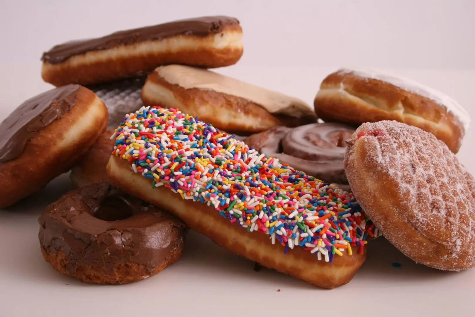 A pile of donuts on a white table.