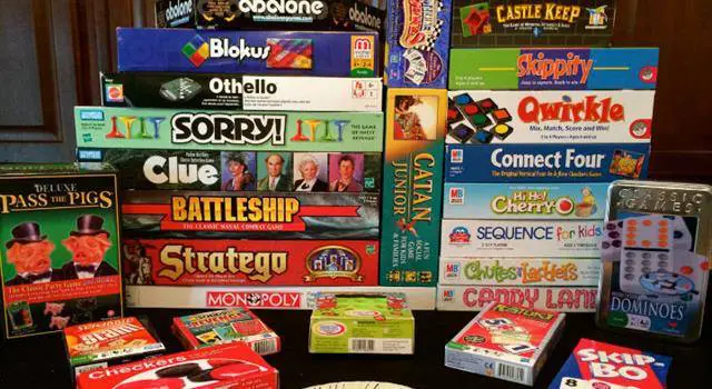A pile of board games on a table.
