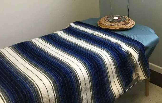 A bed with a blue and white blanket on it.