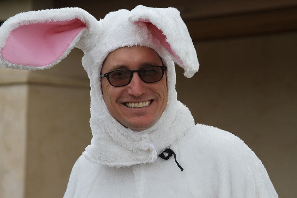 A man in an easter bunny costume smiles.