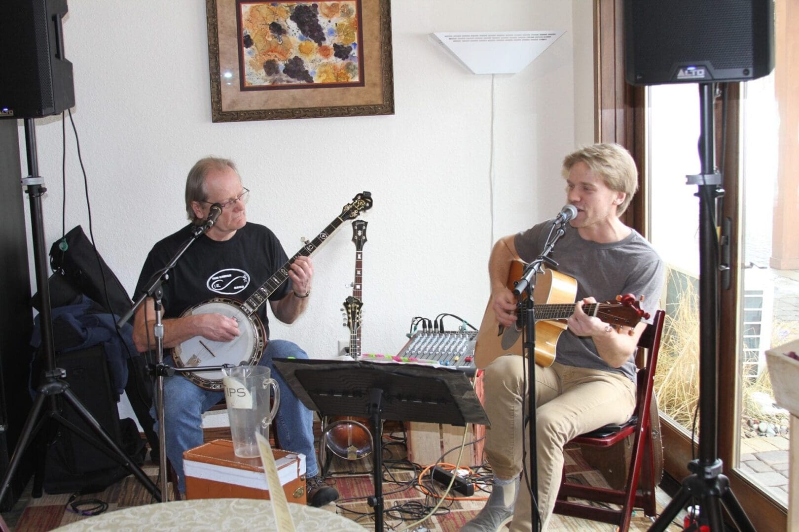 Two men playing guitars in a room.