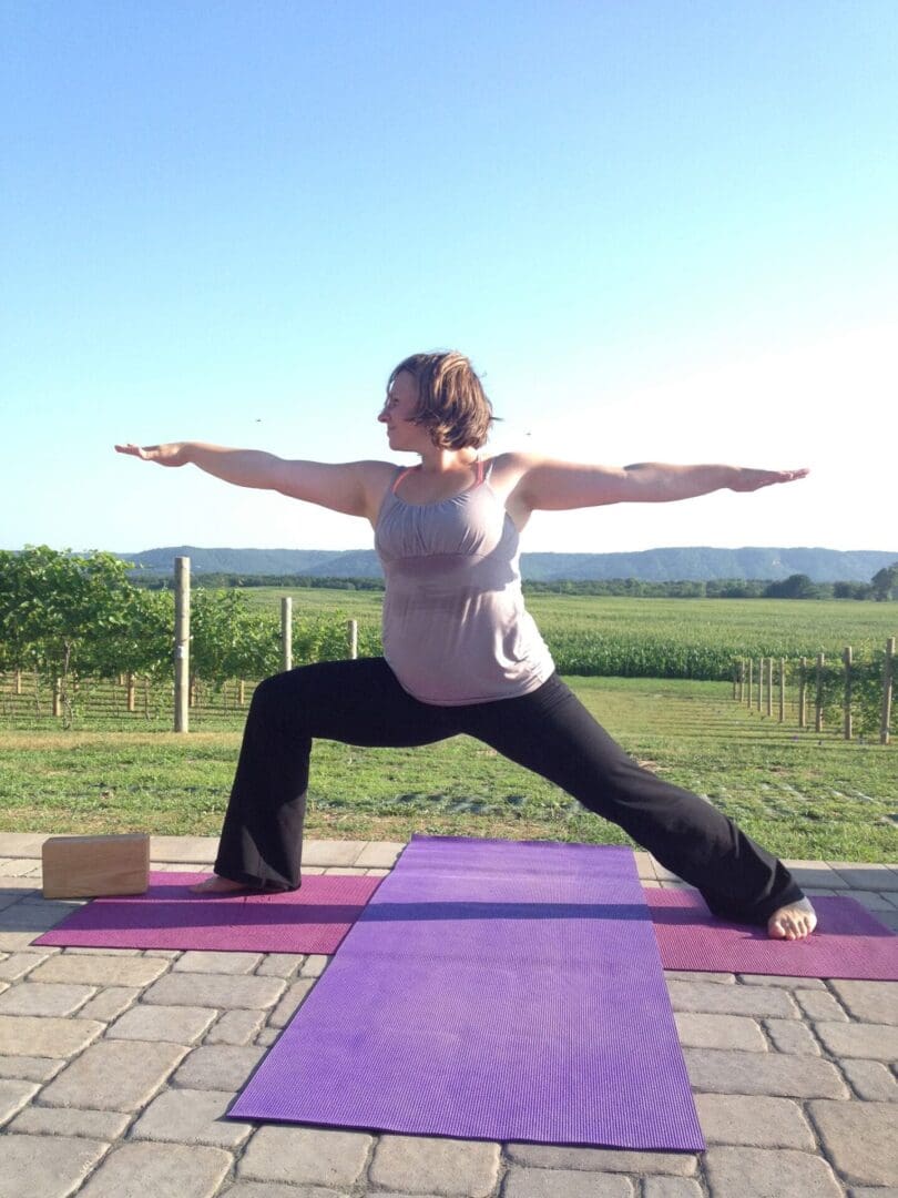 A woman doing yoga in front of a vineyard.