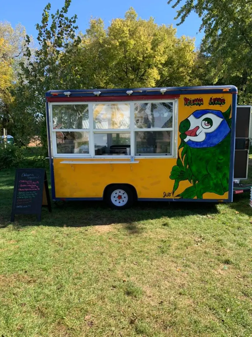 A food truck is parked in a grassy area.