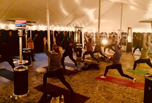 People doing yoga in a white party tent