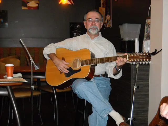 A man playing an acoustic guitar in a coffee shop.