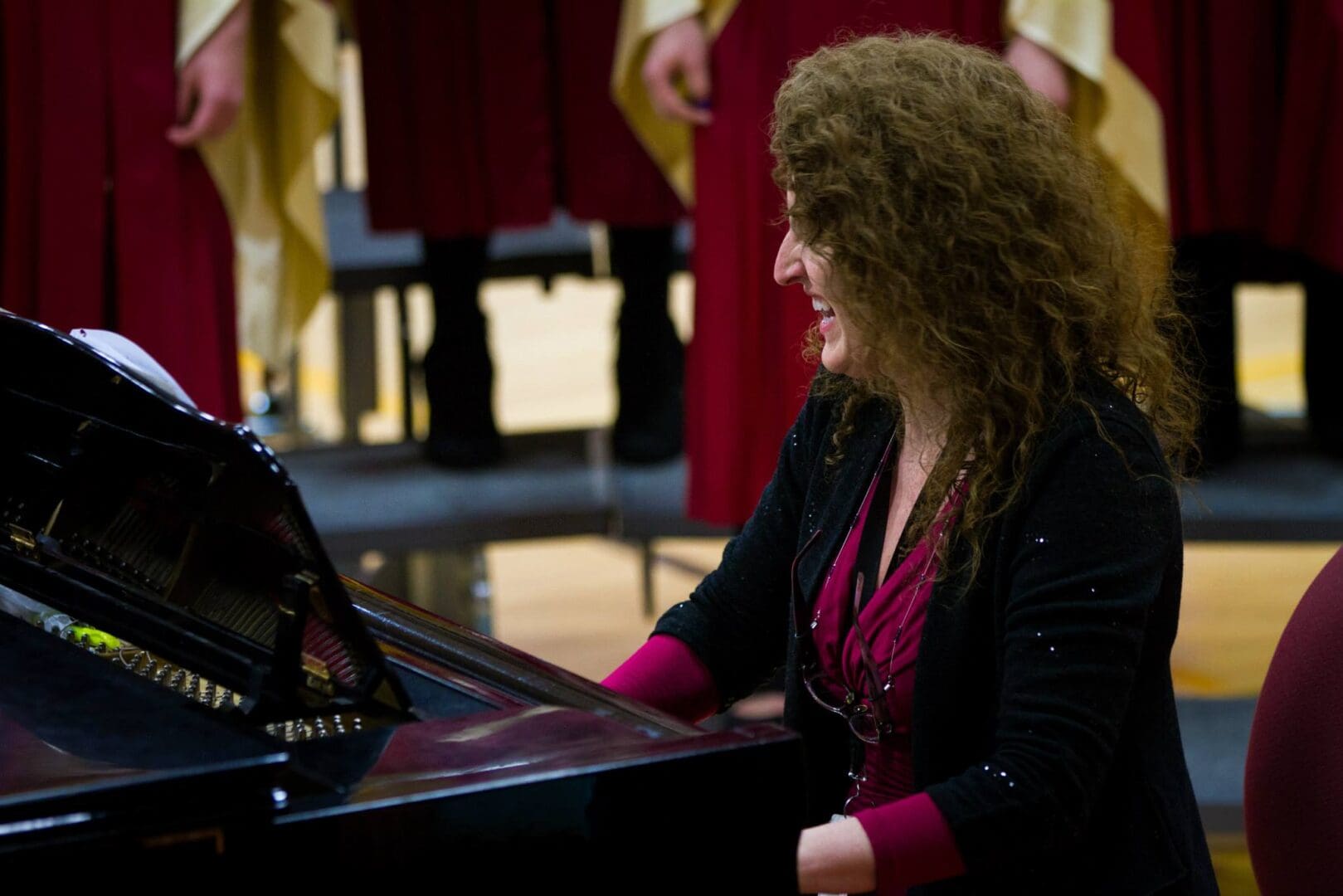 A woman playing a piano in front of a choir.