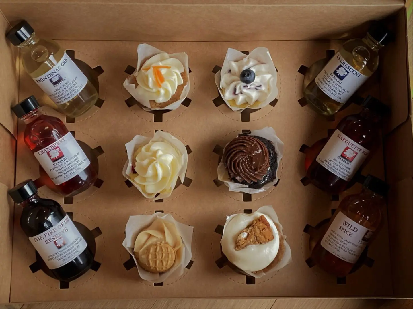 A box filled with cupcakes and a bottle of syrup.