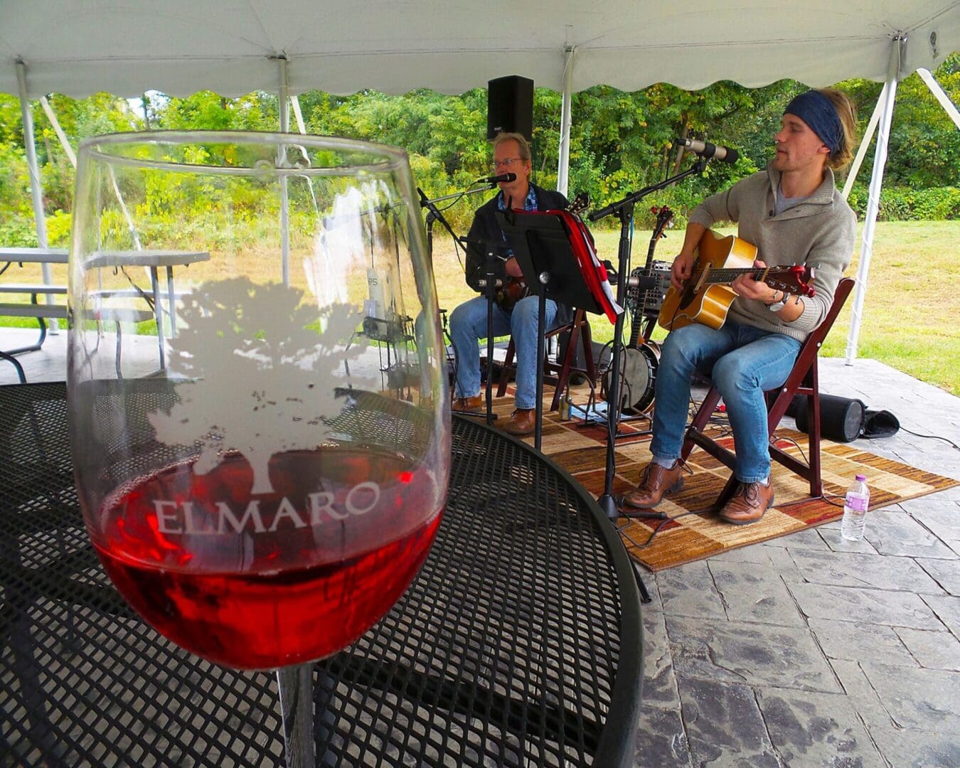 A glass of wine on a table next to a guitar.