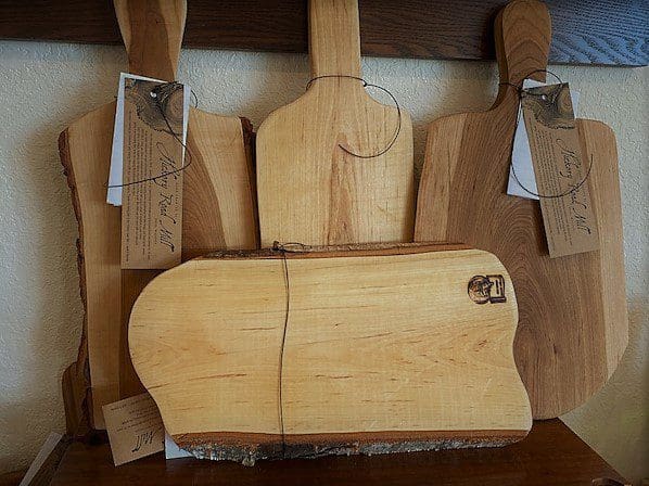 Four wooden cutting boards hanging on a wall.