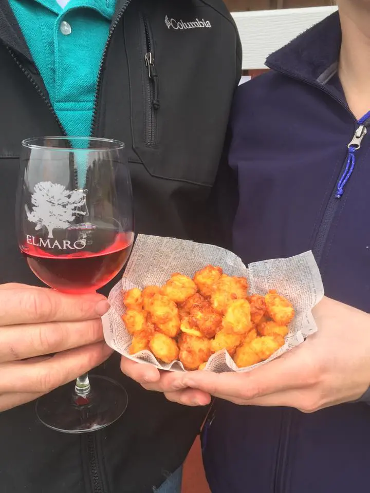 Two people holding cheese curds and wine