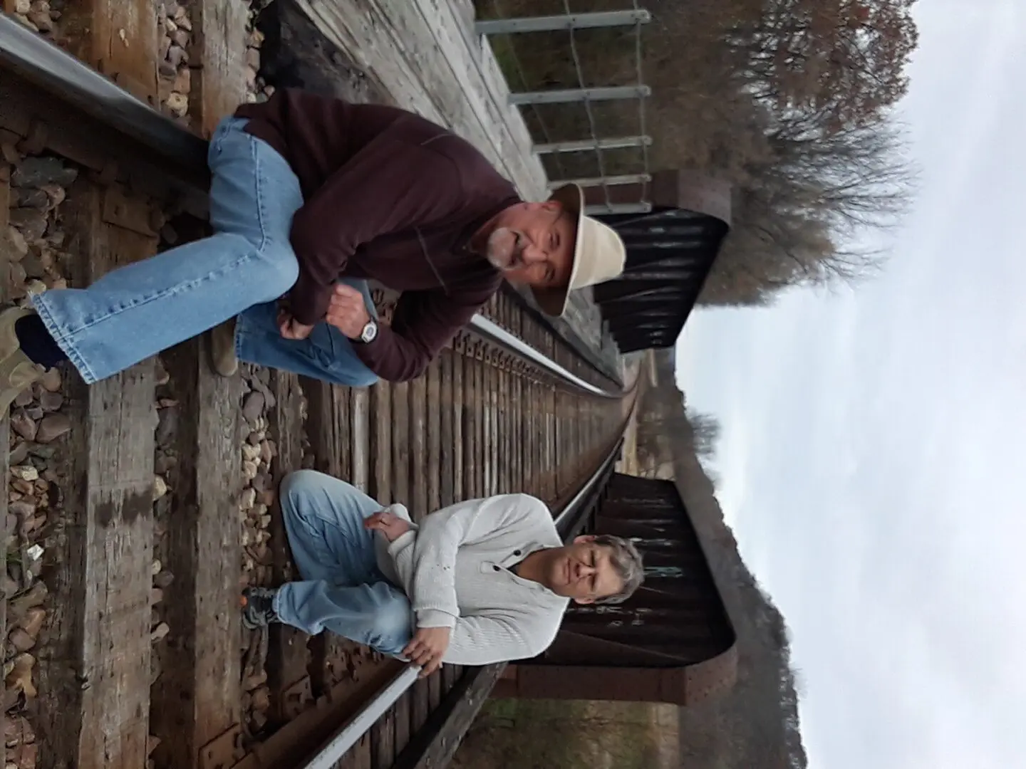 Two men posing on a railroad track.