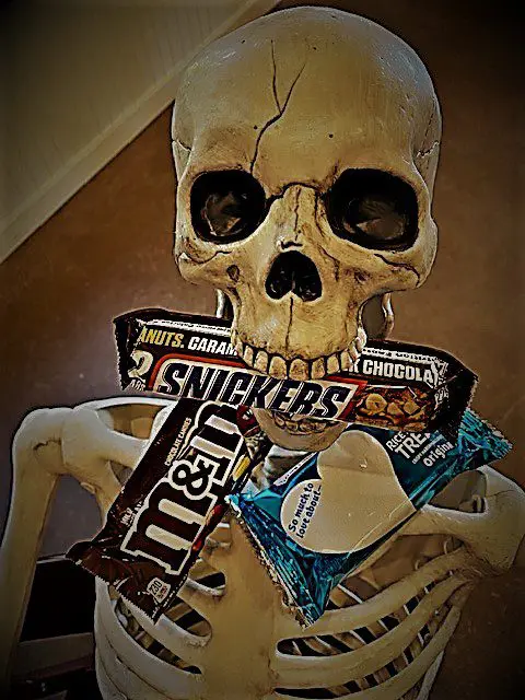 A skeleton with a candy bar in his mouth.