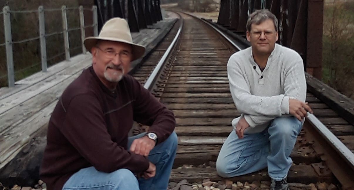 two men sitting on the railway track