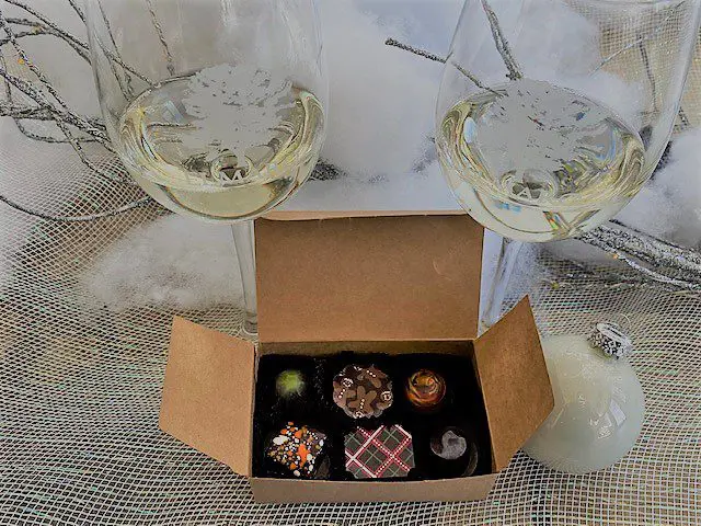 two glasses of white wine and a box of truffle