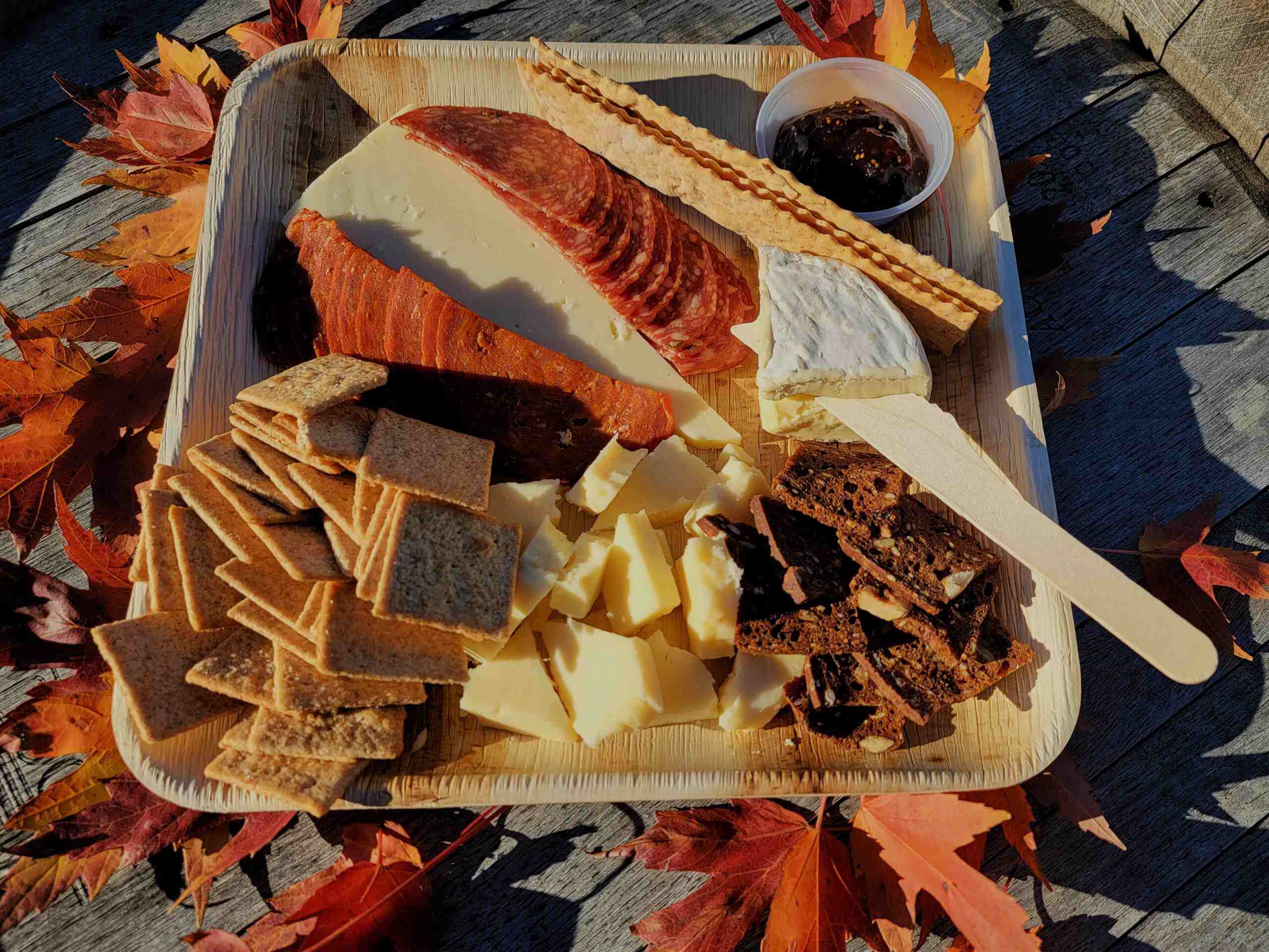 A tray of cheese, crackers and crackers on a wooden table.