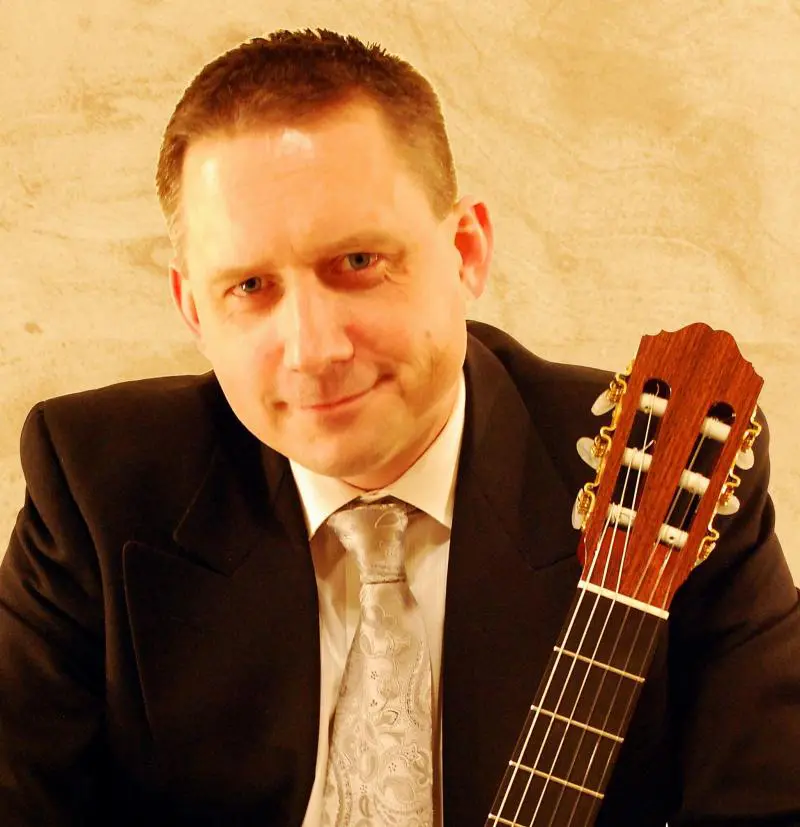 A man in a formal attire with a guitar