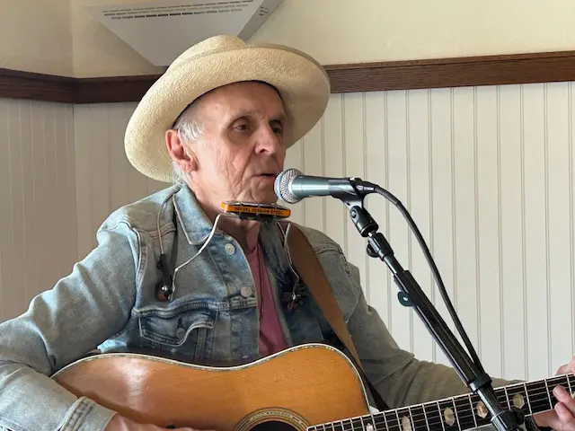 Man in hat singing into a microphone.