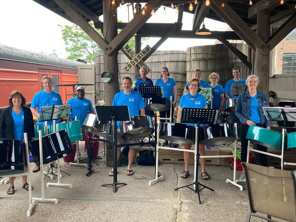 Steel drum band playing under a railroad crossing sign.