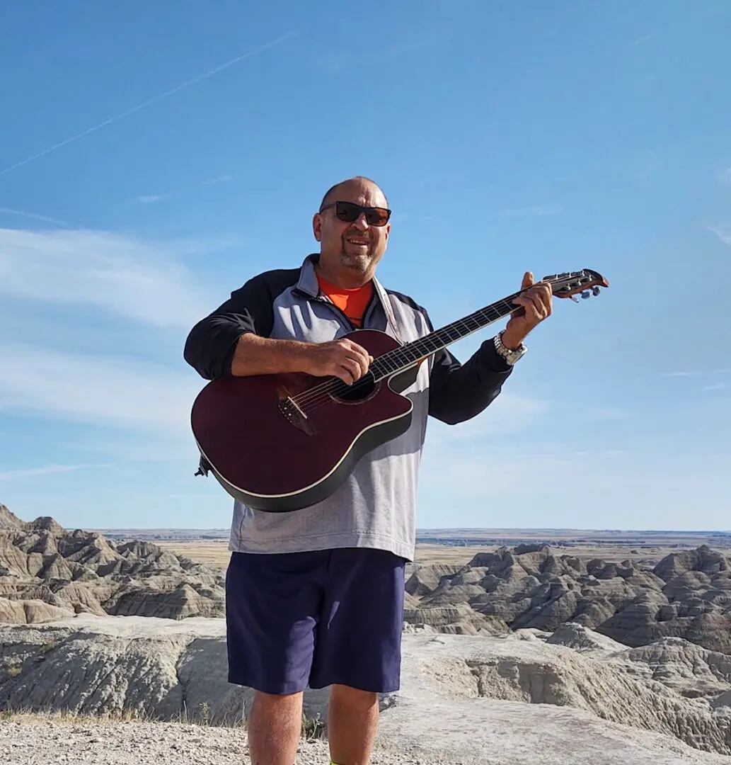 Man playing guitar on a cliff.